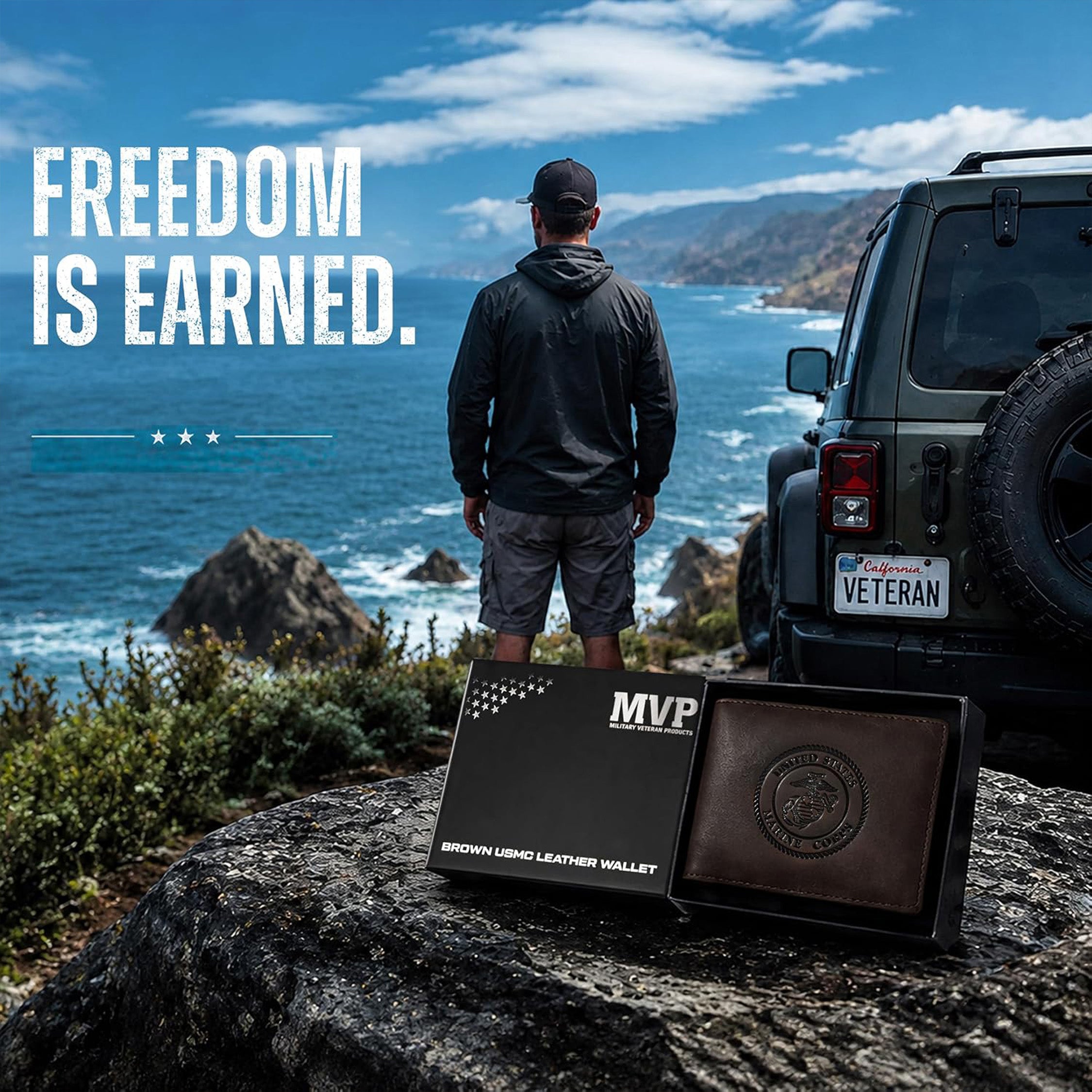 A man stands on a rocky cliff overlooking the ocean with a Jeep behind him, while the foreground shows a boxed brown leather wallet and an open wallet on a rock. Large text reads 'FREEDOM IS EARNED.